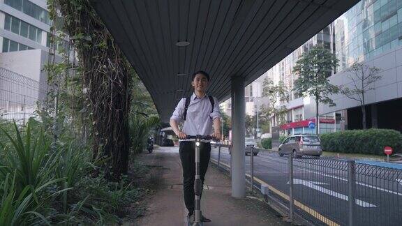 亚洲华人商人穿着电动滑板车在城市上班