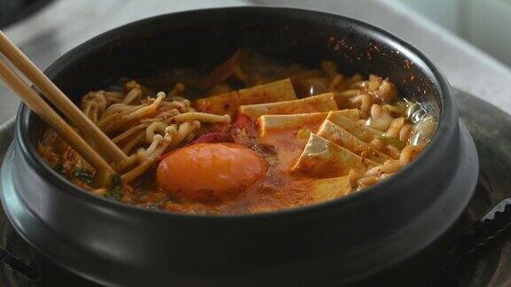 韩式辣面汤以泡菜、豆腐、鸡蛋和蘑菇在韩式石碗中烹饪用筷子吃