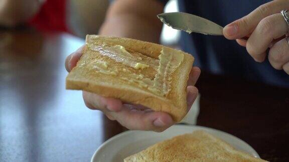手拿着面包和黄油做早餐