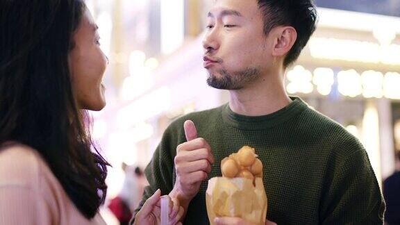 SLOMO手持近距离拍摄一对年轻夫妇在香港吃传统街头小吃