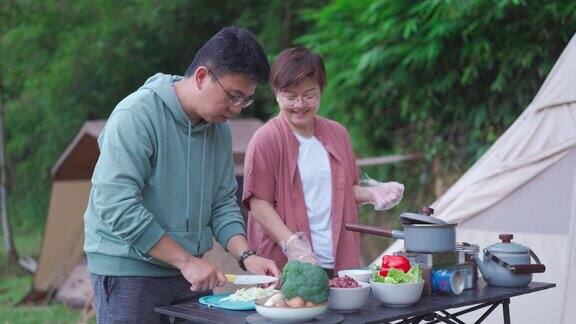 周末早上亚洲华人夫妇在露营帐篷旁准备早餐