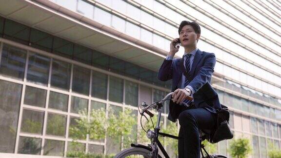 年轻的商人在自行车上使用手机