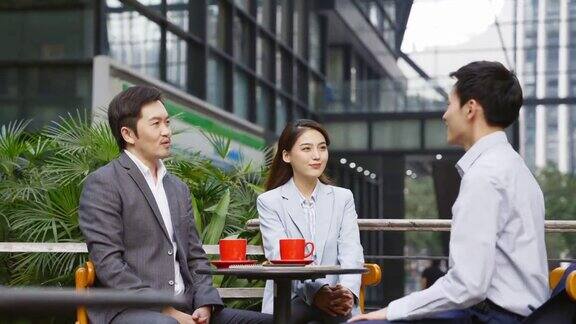 三位亚洲商务人士在户外咖啡馆会面