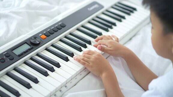 亚洲人在床上和他的狗练习钢琴和电子琴
