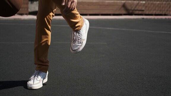在橡胶涂层的篮球场上运球橙色的球黄色的裤子白色的运动鞋