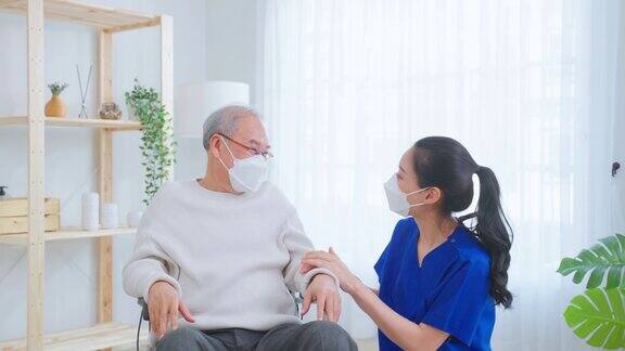 亚洲护理护士的肖像照顾坐在轮椅上的老年男性迷人的专业护理员女士戴上口罩在养老院支持老爷爷照顾微笑着面面相觑