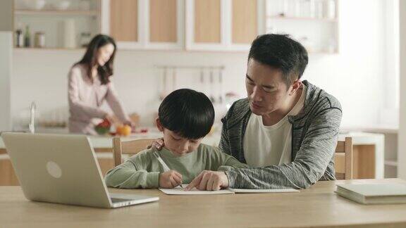 年轻的亚洲父亲在家辅导儿子