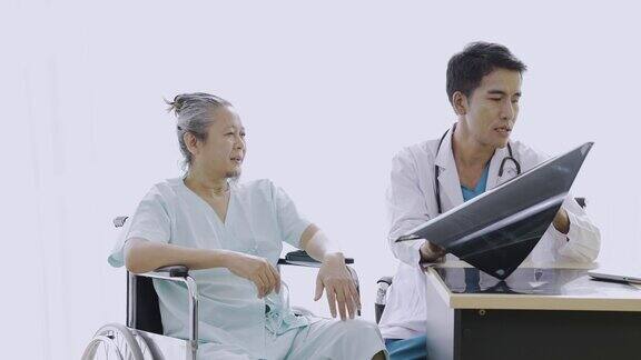 老年病人住院亚洲医生照顾坐轮椅的老年病人专科医生拿着病人的x光片解释疾病诊断