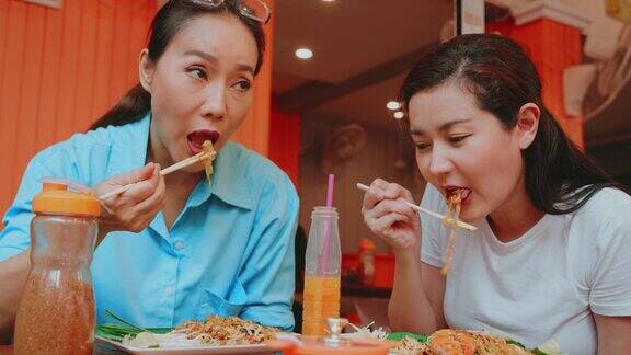 两个女性朋友在泰国度假时喜欢吃泰式炒面