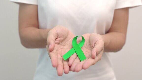 手执绿丝带为肝脏胆囊胆管子宫颈癌肾脏癌症和淋巴瘤宣传月保健和世界癌症日