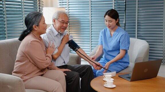 年轻的亚洲成年女性护士检查一位老年病人的血压