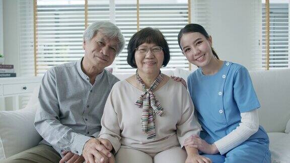 幸福的亚洲老年夫妇与在家庭护理坐在沙发微笑沙发看着相机与享受退休或隔离时间合影亚洲老年人的生活方式
