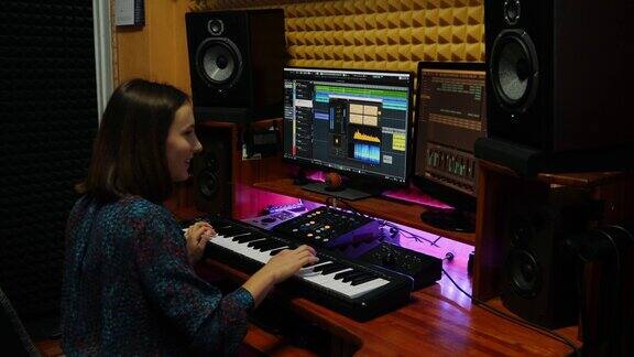在专业录音室弹奏电子钢琴并创作歌曲的女子女音乐家在音响工作室演奏钢琴、迷笛、键盘和mastering音乐创作过程
