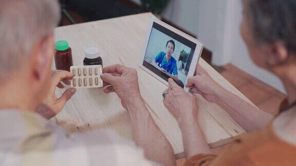 活跃的亚洲老年夫妇在家里用平板电脑与男性医护人员视频通话