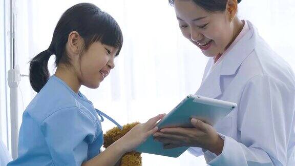 女医生展示数字平板电脑并与年轻的病人女孩谈愉快的情绪