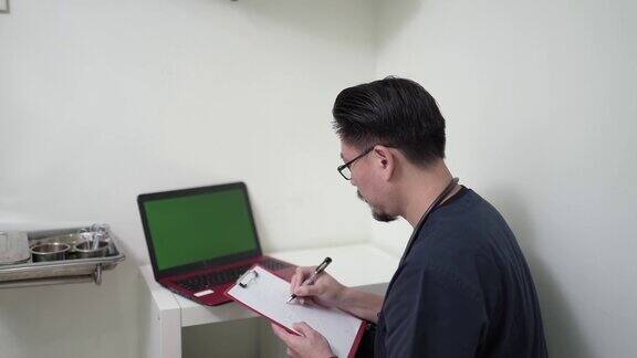 亚裔华人中年男性医生在笔记本电脑上查看病人记录