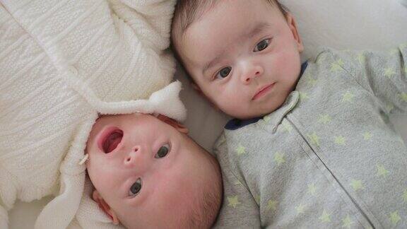 可爱的刚出生的双胞胎宝宝男孩和女孩一起躺在家里的床上