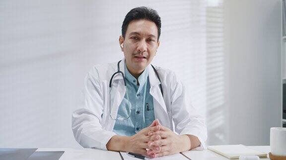 成熟的亚洲男子医生看摄像头视频呼叫医疗结果期间咨询病人在健康诊所