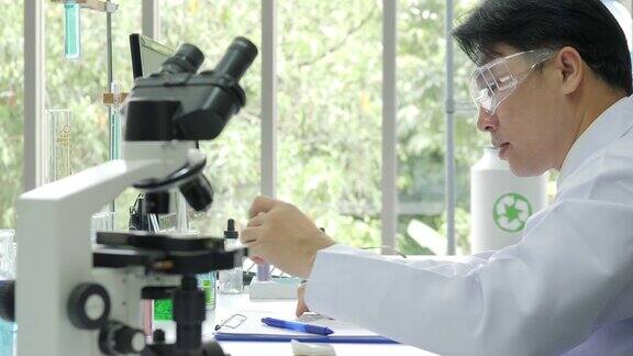 在实验室里通过显微镜观察医学研究的科学家