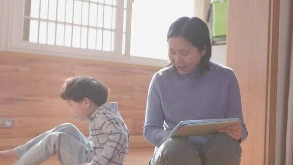 母亲和儿子在客厅用iPad玩游戏