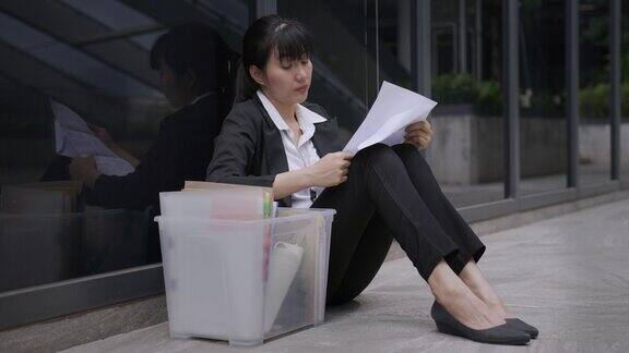 失业的女商人沮丧地坐在办公室附近的地板上做生意