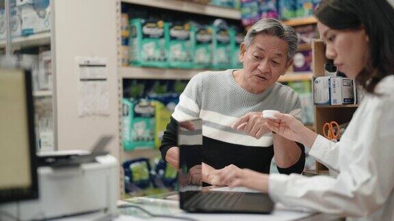 亚洲华裔女药剂师在药房柜台向年长的男性顾客解释