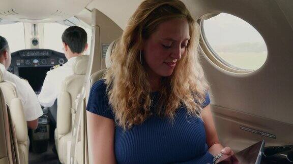 在私人飞机上摆弄平板电脑的年轻女商人