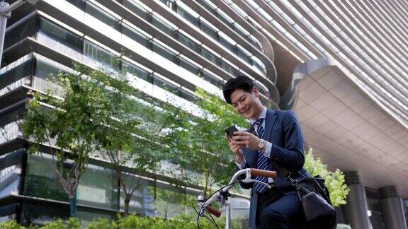 英俊的商人骑着自行车拿着手机
