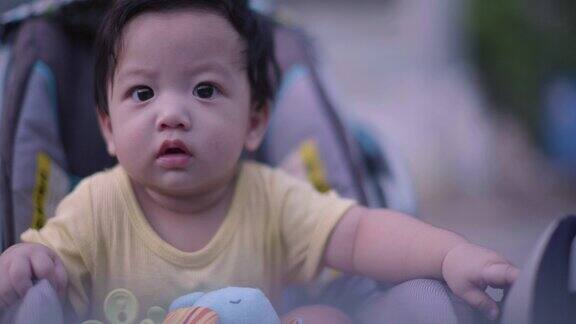 快乐的亚洲小男孩坐在婴儿车上