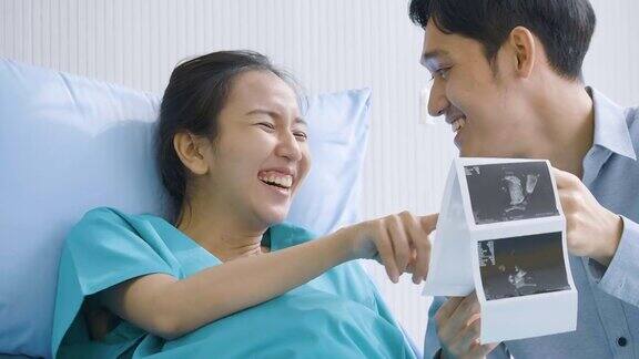 可爱的亚洲夫妇兴奋的父母看超声图
