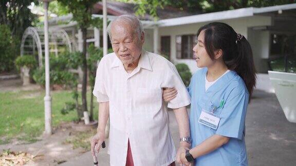 护士协助老年病人在前院散步