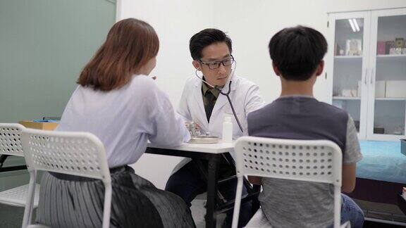 亚洲华人单身母亲带着孩子去看医生医生用听诊器检查儿童心跳