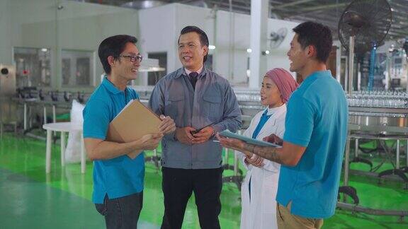 亚洲工厂经理与他的团队在装瓶厂生产线上讨论生产计划