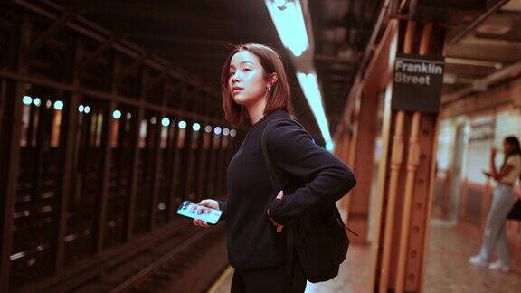导航地铁:亚洲学生策略性地计划她的火车路线手里拿着手机