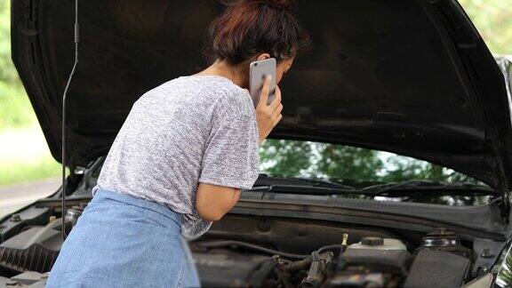 亚洲妇女在看手机和压力妇女后汽车抛锚在街上