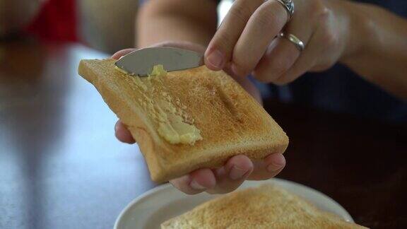 手拿着面包和黄油做早餐