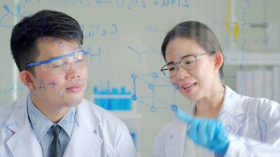科学实验室:在生命科学实验室工作的保健研究人员年轻的男性和年轻的女性化学家自信地在透明的板上绘制配方