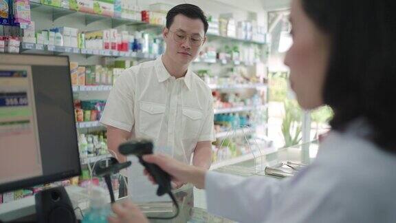亚洲男子顾客在药店扫描支付二维码购买药品