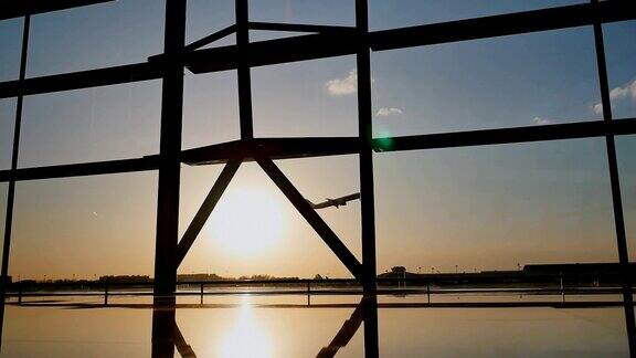 日落时分一架飞机在北京机场的一扇窗户后面起飞