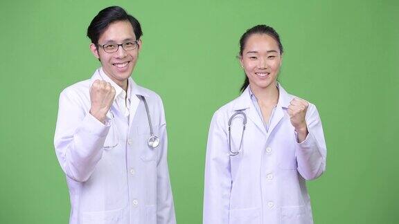 年轻的亚洲夫妇医生与拳头一起举起