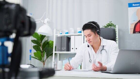亚洲男性医生在家里与病人进行虚拟在线交谈迷人的医生在医院远程工作向病人广播诊断治疗实现远程健康