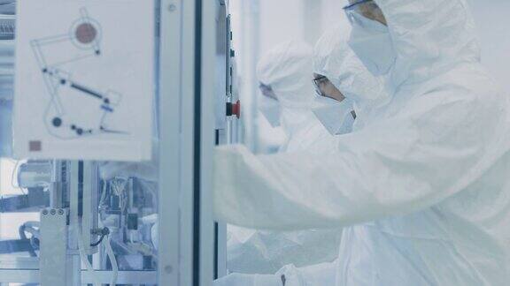 一组科学家穿着无菌防护服在打印机器上工作