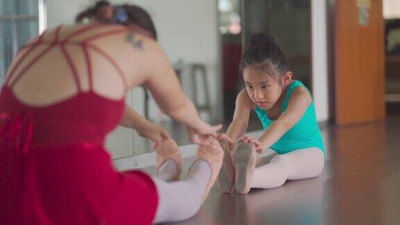 亚洲中国少女芭蕾舞演员训练她的年轻女学生在工作室热身运动