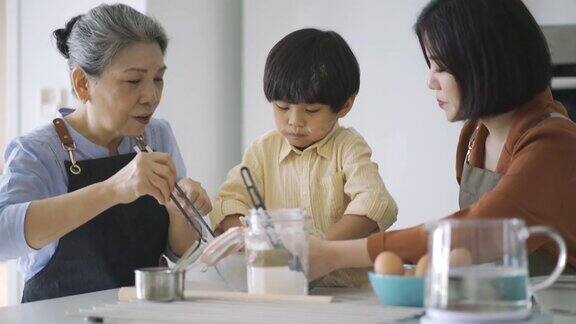 亚洲华人奶奶和妈妈在厨房教孙子烘焙