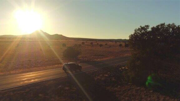 图片:金色的夏日夕阳下一辆黑色SUV行驶在空旷的乡村道路上