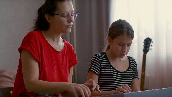 家庭教师教孩子弹钢琴小女孩认真听从老师的指示