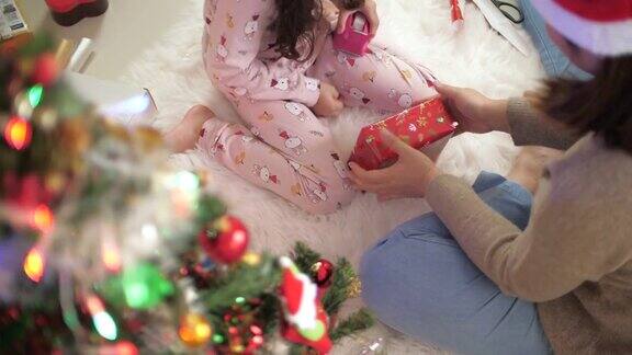 小女孩在妈妈的帮助下为圣诞节打包礼物