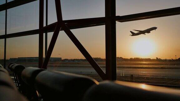 日落时分一架飞机在北京机场的一扇窗户后面起飞