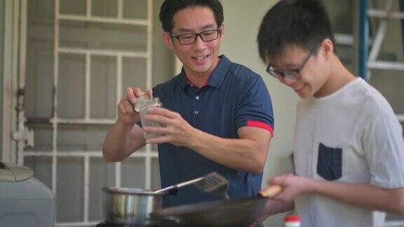 周末一位亚洲华人父亲在自家后院的厨房教儿子做饭准备晚餐