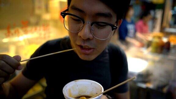 亚洲男子在街头吃鱼丸香港